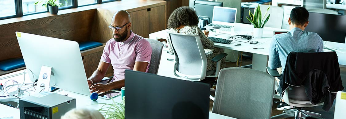 Two colleagues problem-solving at a computer together in the office